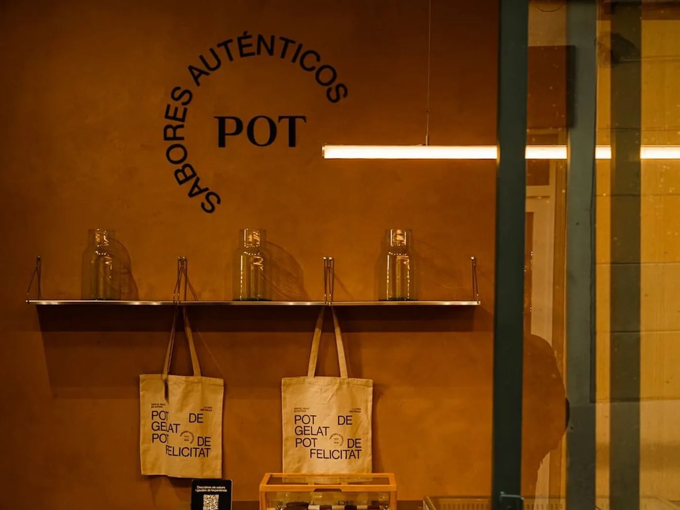 Interior del local de Gràcia, con el mural de Pot y las bolsas de tela sobre el mostrador